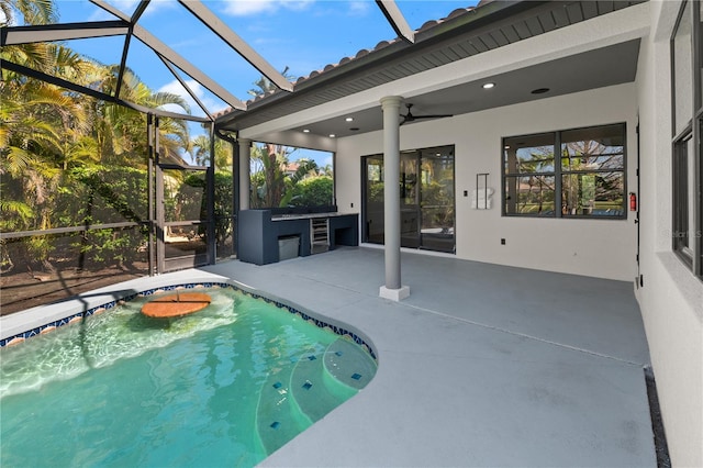 pool with a lanai, a patio, an outdoor kitchen, and ceiling fan