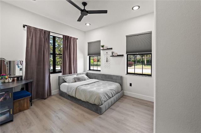 bedroom featuring baseboards, multiple windows, and wood finished floors