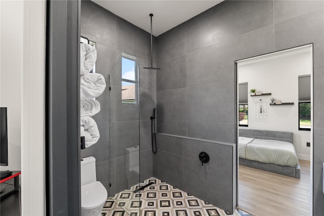 bathroom featuring a healthy amount of sunlight, tiled shower, and wood finished floors