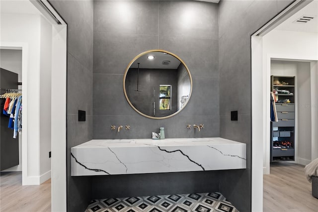 bathroom featuring a walk in closet, tile walls, visible vents, and wood finished floors