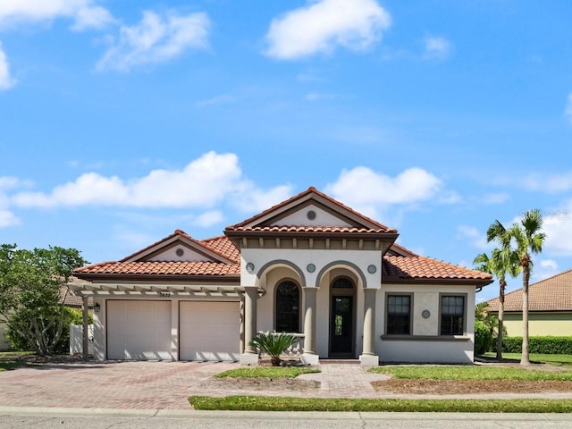 3635 80th Dr E, Sarasota, FL 34243 - mediterranean / spanish house featuring decorative driveway, a tile roof, stucco siding, and an attached garage