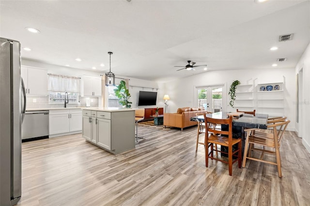 dining space with french doors, visible vents, light wood-style flooring, and vaulted ceiling