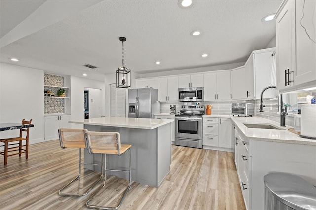 kitchen with a kitchen bar, light wood-type flooring, appliances with stainless steel finishes, and a center island