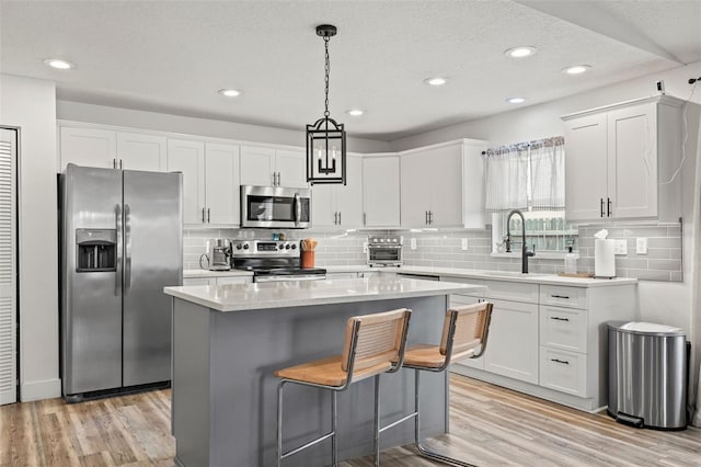 kitchen featuring stainless steel appliances, light wood-style flooring, and white cabinetry