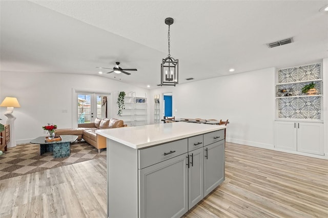 kitchen with visible vents, light wood finished floors, gray cabinets, light countertops, and vaulted ceiling