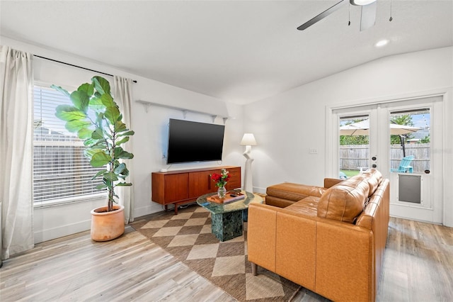 living room featuring french doors, baseboards, light wood-style flooring, and vaulted ceiling