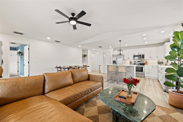 living area with visible vents, recessed lighting, light wood finished floors, ceiling fan, and vaulted ceiling