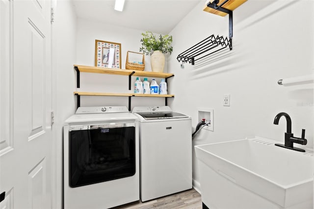 washroom featuring laundry area, washing machine and dryer, light wood-type flooring, and a sink