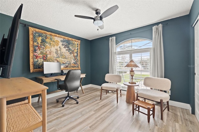 office space with light wood-type flooring, baseboards, and a textured ceiling