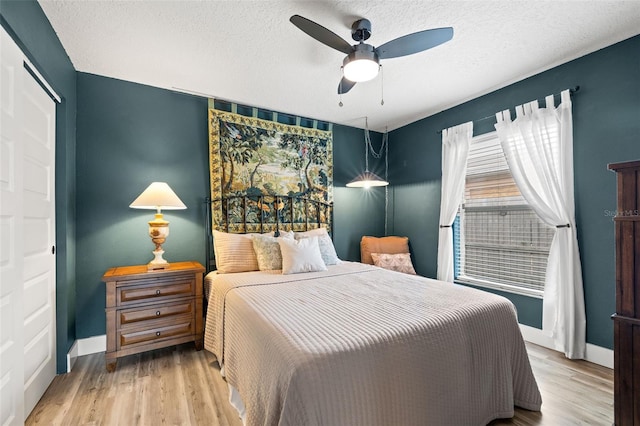 bedroom featuring a textured ceiling, baseboards, and wood finished floors