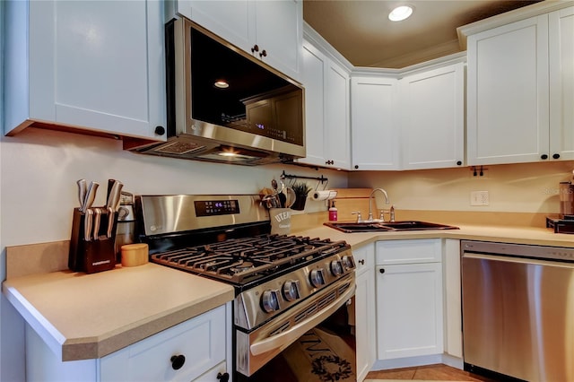 kitchen featuring a sink, stainless steel appliances, white cabinetry, and light countertops