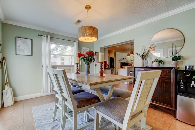 dining space with light tile patterned floors, visible vents, a textured ceiling, and ornamental molding