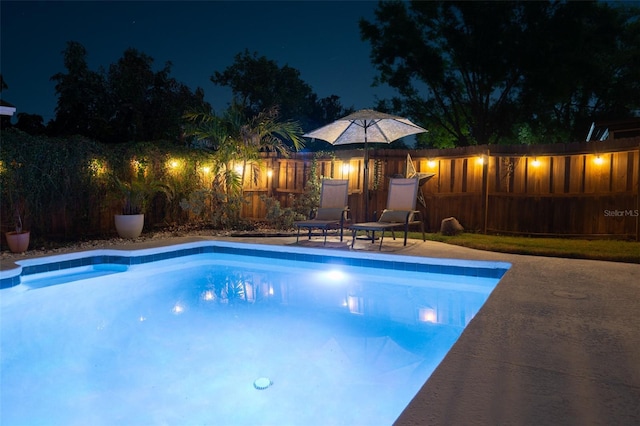 pool at twilight featuring a fenced backyard and an outdoor pool