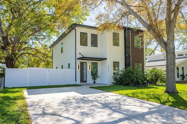 contemporary home with stucco siding, a front lawn, and fence