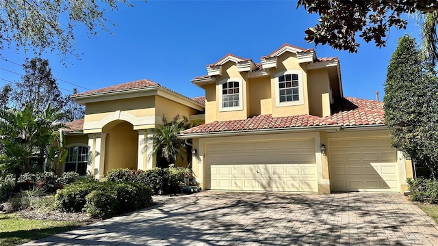 mediterranean / spanish-style house featuring stucco siding, decorative driveway, and a tile roof