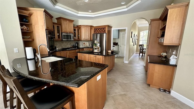 kitchen featuring open shelves, arched walkways, a raised ceiling, and stainless steel appliances