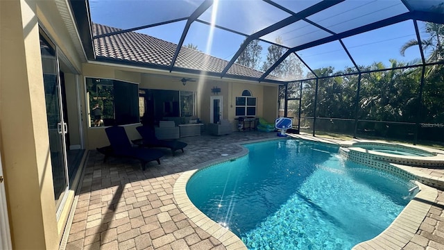 view of swimming pool with a patio area, glass enclosure, a pool with connected hot tub, and ceiling fan