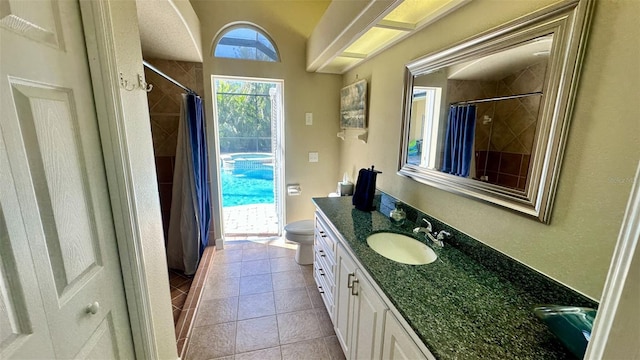 bathroom featuring vanity, tile patterned floors, toilet, and tiled shower