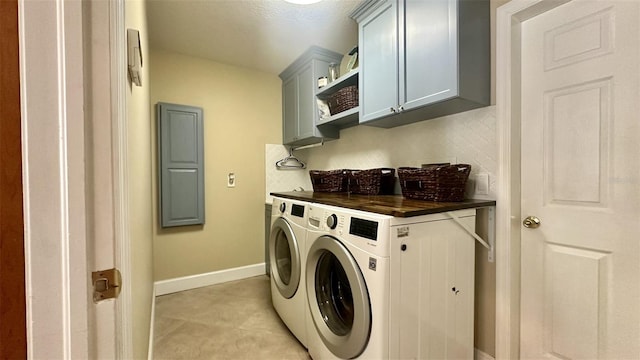 washroom featuring cabinet space, baseboards, and washer and clothes dryer