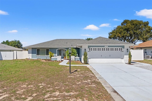 ranch-style home with a front yard, fence, driveway, stucco siding, and a garage