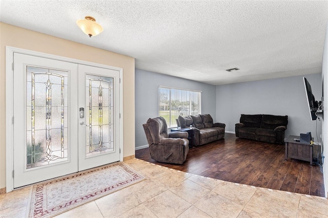 tiled foyer entrance with french doors, baseboards, a textured ceiling, and visible vents