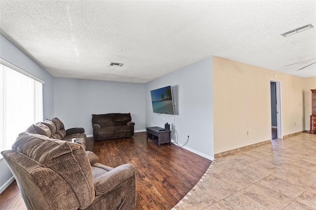 living room with visible vents, a textured ceiling, and wood finished floors