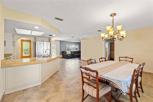 dining room featuring a wealth of natural light, visible vents, arched walkways, and a textured ceiling