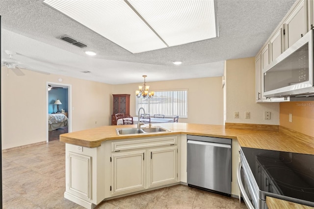 kitchen with visible vents, a peninsula, a sink, stainless steel appliances, and light countertops