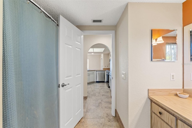 bathroom featuring tile patterned flooring, visible vents, curtained shower, vanity, and a textured ceiling