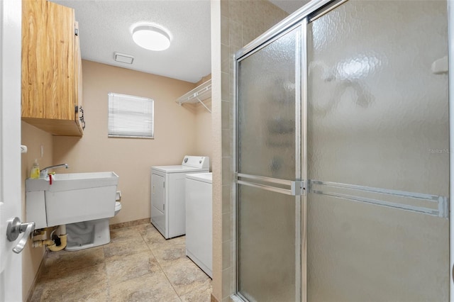 laundry room featuring washer and dryer, a textured ceiling, cabinet space, and a sink