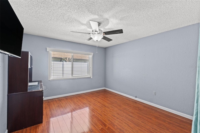 unfurnished bedroom with a textured ceiling, a ceiling fan, baseboards, and wood finished floors