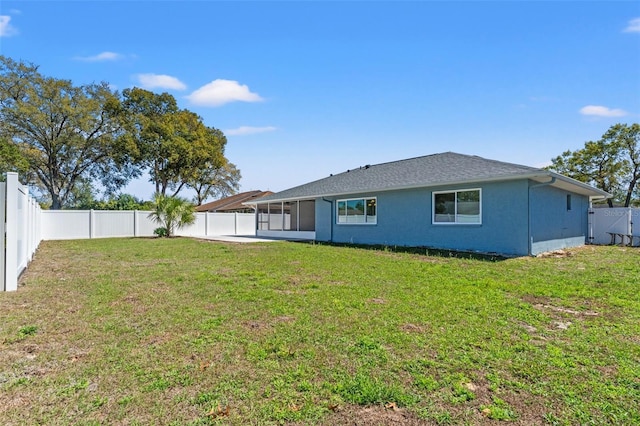 rear view of property featuring a yard, stucco siding, a fenced backyard, and a sunroom