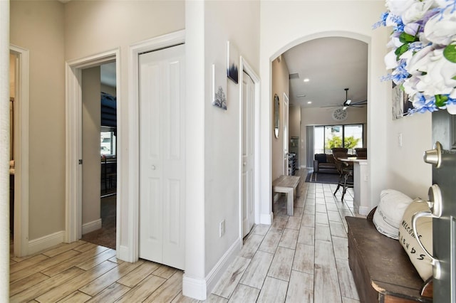 hall featuring arched walkways, recessed lighting, baseboards, and wood tiled floor