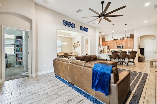 living area with arched walkways, wood finish floors, visible vents, and ceiling fan