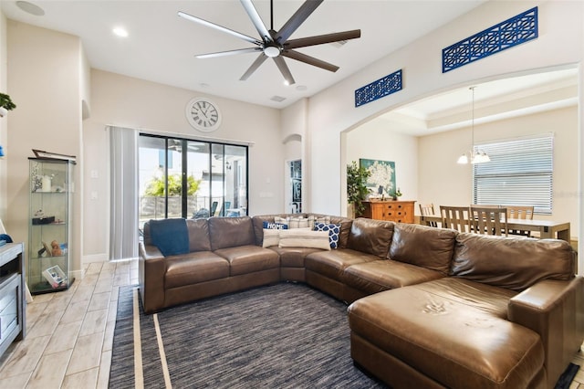 living room featuring wood finish floors, ceiling fan with notable chandelier, recessed lighting, arched walkways, and baseboards