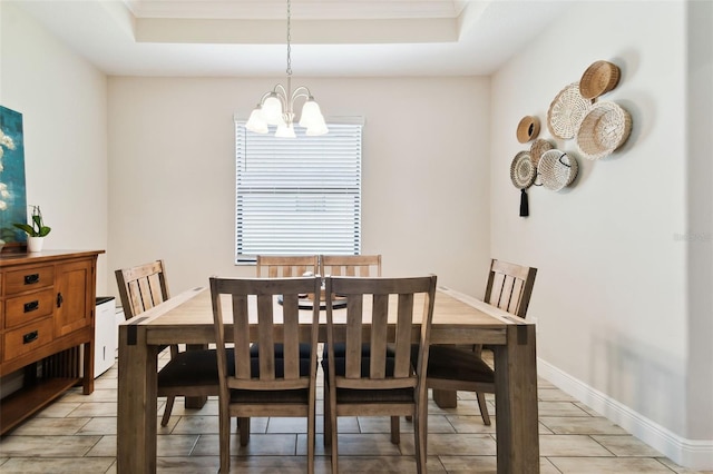 dining area with a tray ceiling, baseboards, and a notable chandelier