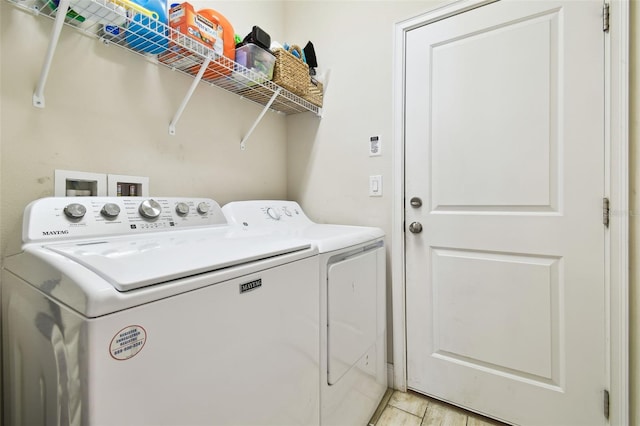 washroom with laundry area, washer and dryer, and light wood-type flooring