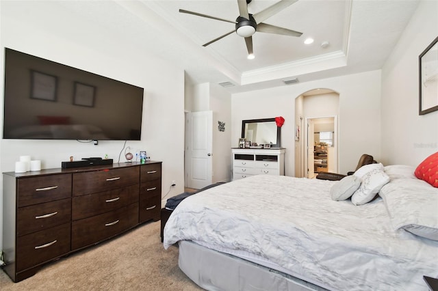 bedroom with visible vents, ornamental molding, a tray ceiling, arched walkways, and light colored carpet