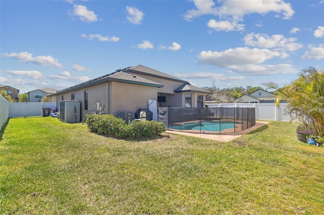 rear view of house with stucco siding, a yard, a fenced in pool, and a fenced backyard