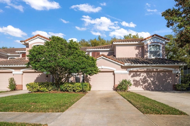 mediterranean / spanish-style house with stucco siding, a tiled roof, concrete driveway, and a garage