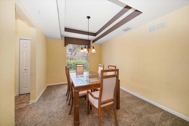 dining space with a raised ceiling, a notable chandelier, baseboards, and visible vents