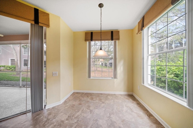 unfurnished dining area featuring plenty of natural light and baseboards