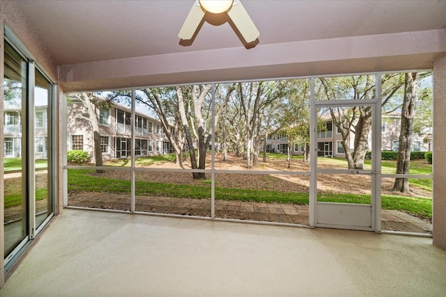 unfurnished sunroom featuring a ceiling fan