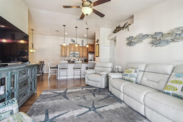 living room with visible vents, ceiling fan, vaulted ceiling, and dark wood-type flooring