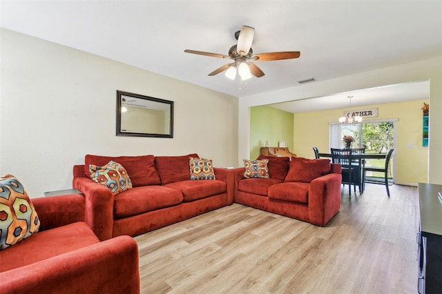 living room with light wood-style flooring, ceiling fan with notable chandelier, and visible vents