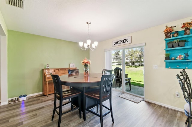 dining space featuring visible vents, baseboards, an inviting chandelier, and wood finished floors