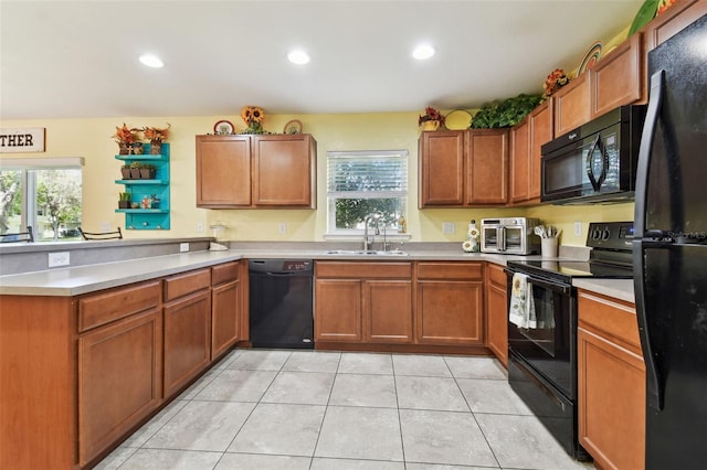 kitchen featuring brown cabinetry, a peninsula, a sink, black appliances, and light countertops