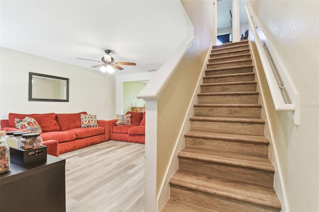 stairs featuring wood finished floors and a ceiling fan