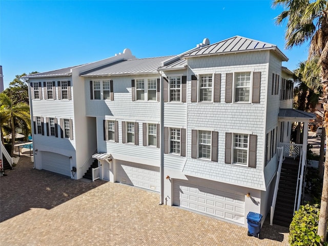 view of front of house featuring stairs, metal roof, decorative driveway, a garage, and a standing seam roof