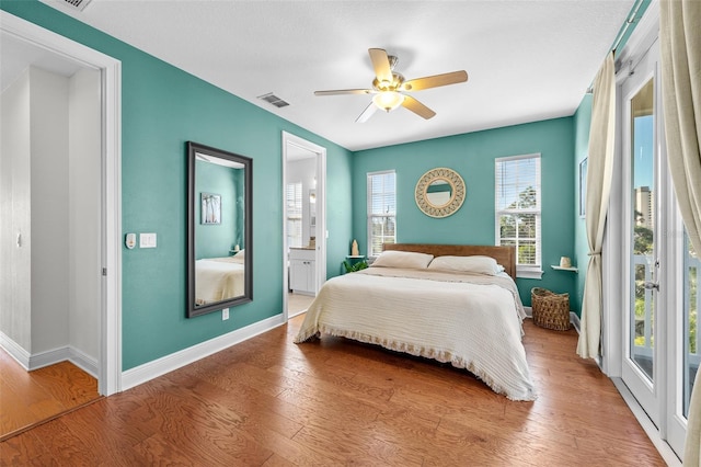 bedroom featuring visible vents, ensuite bathroom, a ceiling fan, wood finished floors, and baseboards